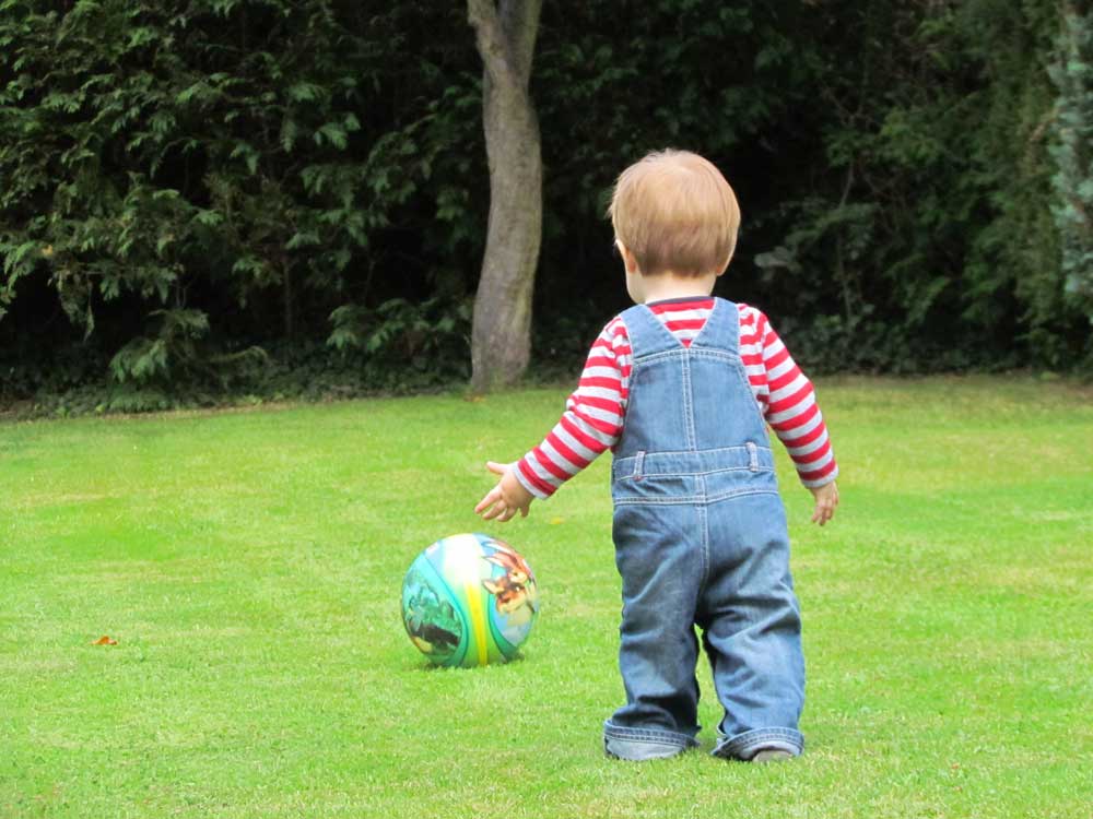 мальчик в возрасте 1 год идет за мячом